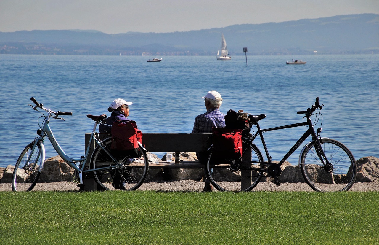 couple de seniors assis sur un banc devant la mer, ils font une pause lors d'une ballade à vélo