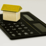 Petite maison posée sur une calculatrice pour symboliser le patrimoine comme outil de financement
