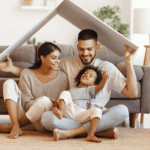 Famille souriante formant un toit symbolique avec un panneau, illustrant la protection offerte par l’assurance emprunteur.