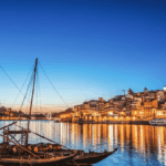 Bateaux traditionnels Rabelo sur le fleuve Douro à Porto, Portugal, au crépuscule. La rive de Vila Nova de Gaia est entièrement illuminée, reflétant les